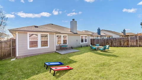 Fenced backyard with patio seating, a lawn, and lawn games