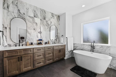 Bathroom with a freestanding tub, double vanity, and marble-patterned walls