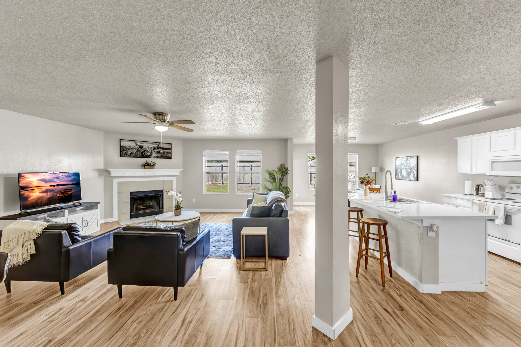 Open living room with dark seating, a fireplace, and an adjoining kitchen in a managed home