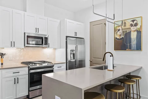 White kitchen with a gas range, microwave, refrigerator, and breakfast-bar seating