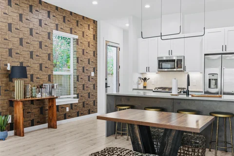 Wood dining table beside a white kitchen and patterned accent wall